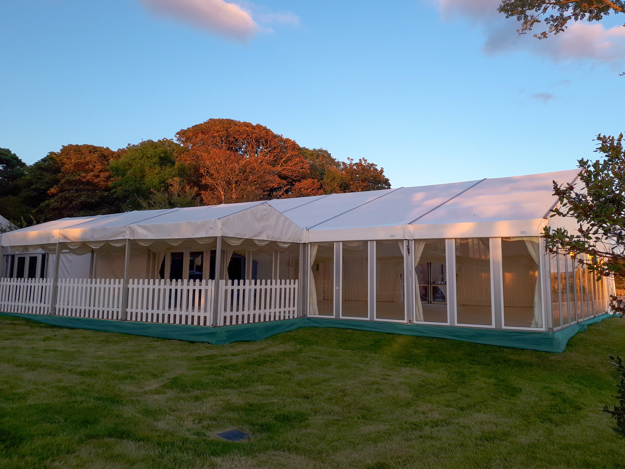 A large marquee in morning light with glass walls and a canopy entrance